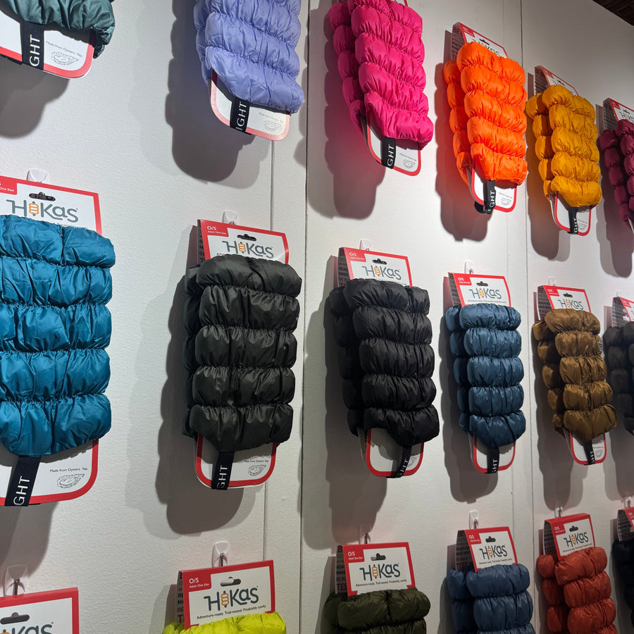 Hikas gaiters of all colors on retail packaging, being displayed in a retail setting hanging on a white wall.