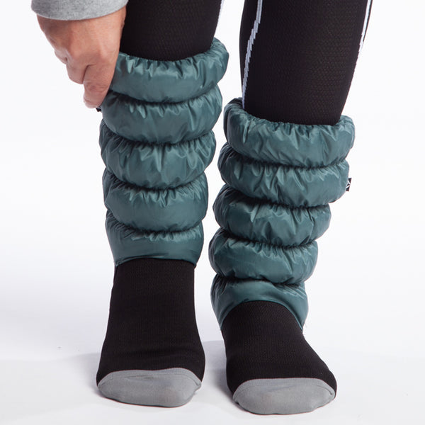 Hikas Gaiter in Blue Spruce front view right foot is on ball of the foot and right hand is reaching from the top of the frame to grab the top of the right Hika. 