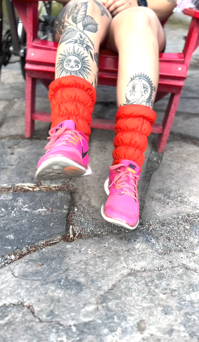 Person sitting in an Adirondack chair dangling their feet wearing hot pink Nike sneakers and Very Vermillion Hikas Gaiters.